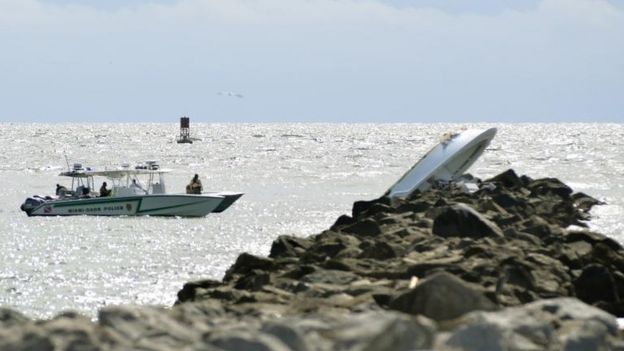Embarcación volcada sobre una escollera.