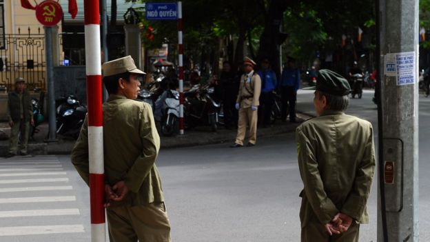 Police and militiamen stand guard at an intersection where buses transporting delegates attending a local communist party congress are expected to ride past in downtown Hanoi on November 2, 2015.