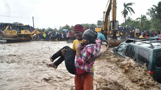 Homem carrega mulher nos braços em meio a lama deixada pelo furacão no Haiti