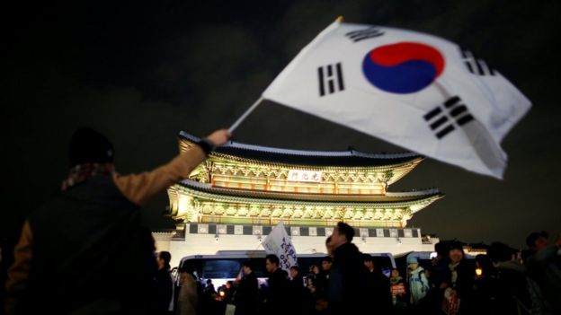 A man waves a national flag as people march toward the Presidential Blue House during a rally demanding President Park Geun-hye to step down