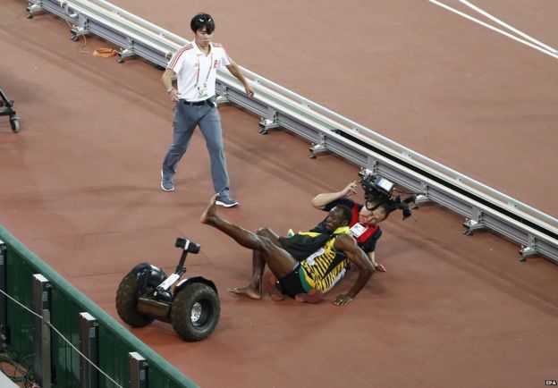 Usain Bolt of Jamaica falls over after a TV cameraman with a segway drove into him after the men