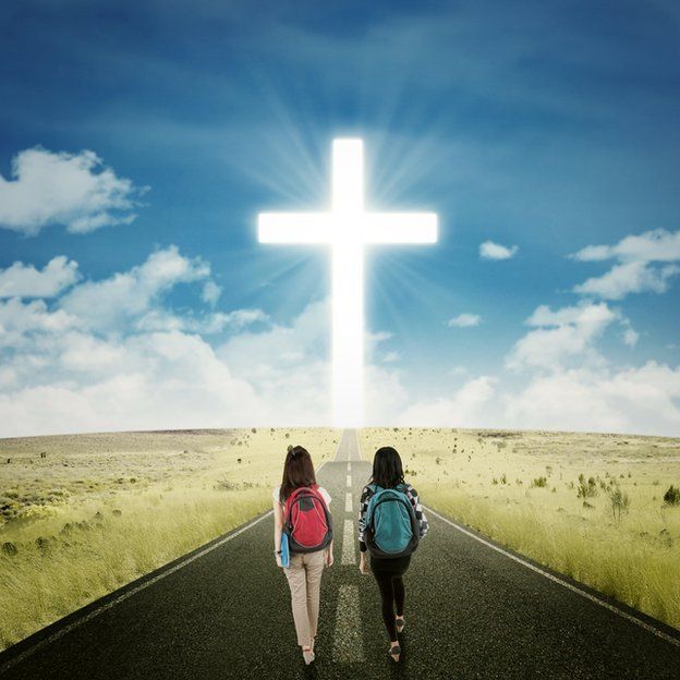 Dos niñas escolares caminando en dirección a la cruz cristiana