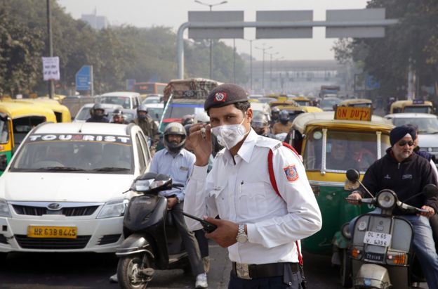 A traffic police man stands at traffic lights wearing a pollution mask during the first day of the implementation of the odd-even scheme for the vehicles in Delhi, India, 1 January 2016
