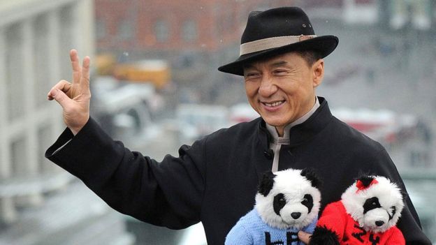 Hong Kong action film star Jackie Chan holds toy pandas as he poses for photos atop a hotel roof just outside the Kremlin in Moscow