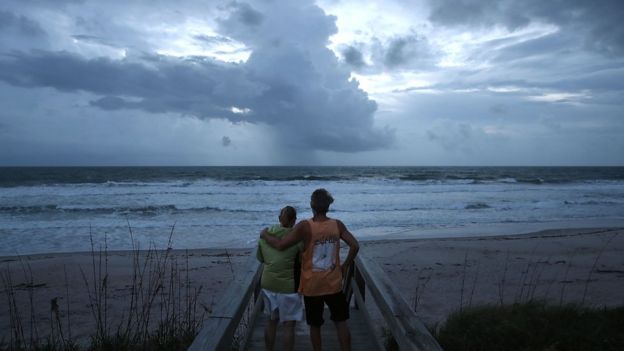 Una pareja mira el cielo nublado en Satellite Beach, Florida