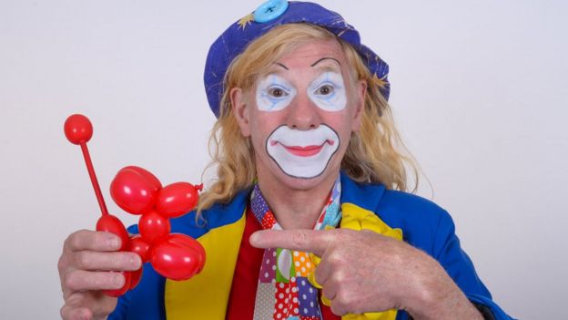 Pat the Clown wearing traditional face paint and holding a balloon