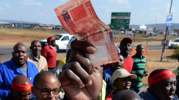 Someone holding a rand note.