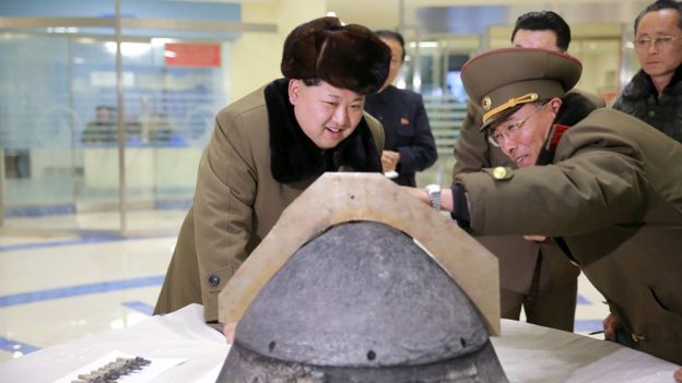 North Korean leader Kim Jong-un looks at a rocket warhead tip after a simulated test of atmospheric re-entry of a ballistic missile, at an unidentified location in this undated photo released by North Korea