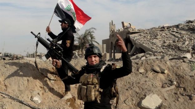 Iraqi security forces raise an Iraqi flag near the provincial council building in central Ramadi (27 December 2015)