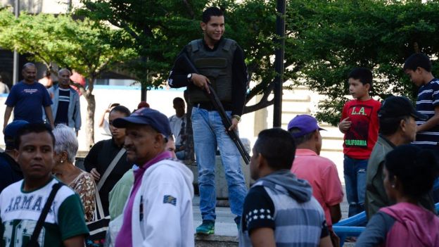 Un agente armado frente a una fila en Caracas