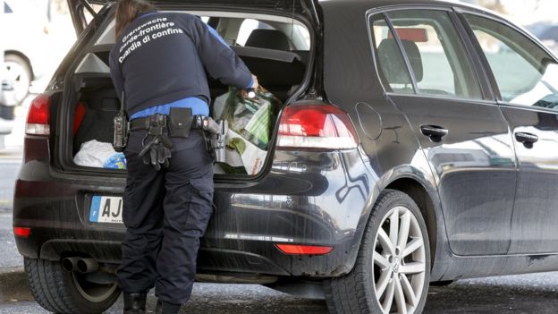 A Swiss border guard checks a car at the French-Swiss border near Geneva, Switzerland, Friday, Dec 11, 2015