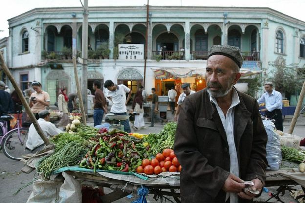 A Muslim Uighur vendor counts money beside his vegetable stall in Kashgar, 16 September 2003, in northwest China's Xinjiang province.