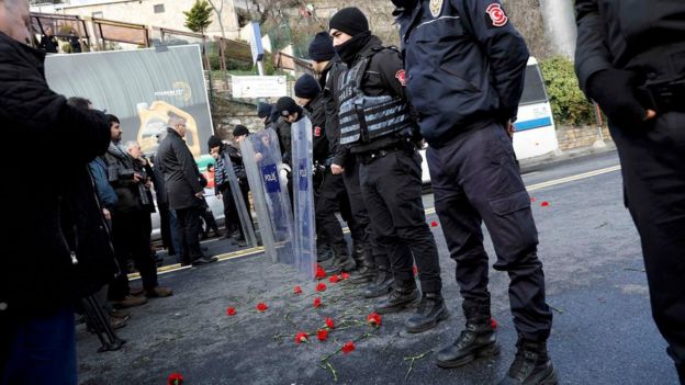 Flowers are placed next to Turkish police officers as they stand guard near the Reina nightclub, which was attacked by a gunman, in Istanbul, Turkey, on 1 January 2017