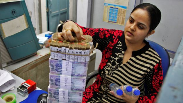 Mujer en un banco con fajos de billetes