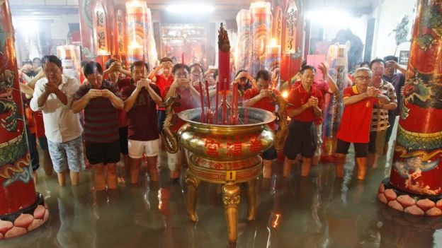 Indonesian men of Chinese descent pray at a flooded temple following a heavy rain during the Lunar New Year