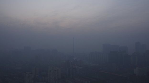 A chimney is seen near residential buildings amid heavy smog under a red alert for air pollution, in Beijing, China, December 19, 2015.