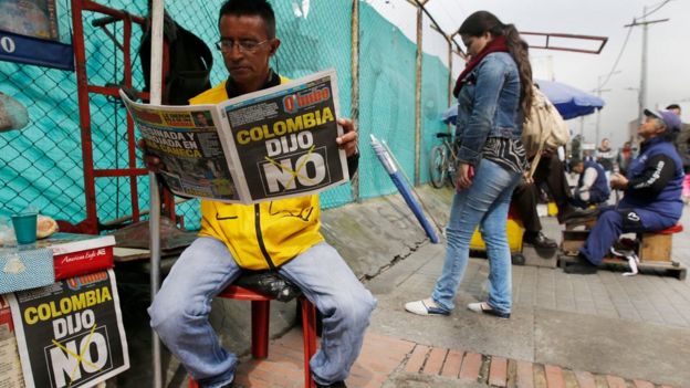 A man reads a newspaper with the headline that reads in Spanish: 