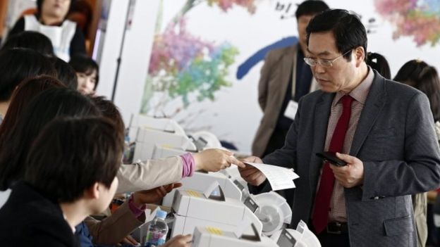 A South Korean man receives his ballot to cast at polling station in Seoul (08 April 2016)