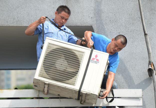 Hombres bajando un aire acondicionado.