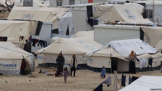 Syrian refugees standing next to tents at the UN-run Zaatari refugee camp, north east of the Jordanian capital Amman