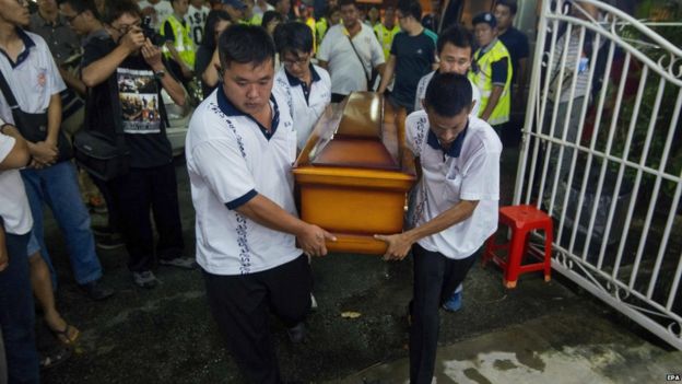 Funeral workers carry a coffin on 20 August 2015