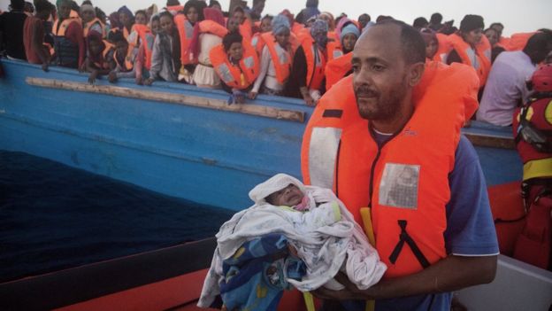 A man carries his five-day-old son after been rescued from a crowded wooden boat as they were fleeing Libya, during a rescue operation at the Mediterranean sea, about 13 miles north of Sabratha, Libya, Monday 29 August 2016