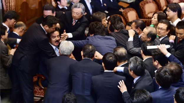 Opposition lawmakers surrounding chairman Masahisa Sato during the upper house's ad hoc committee meeting on the controversial security bills