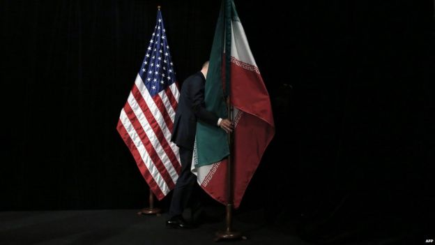A man moves the Iranian flag past the US flag at the Austria International Centre in Vienna (14 July 2015)