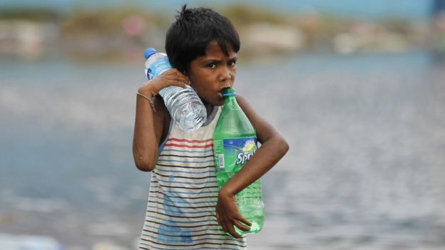 A Sri Lankan boy carries water bottles near a flood affected area near Colombo, Sri Lanka, Sunday, May 22, 2016.