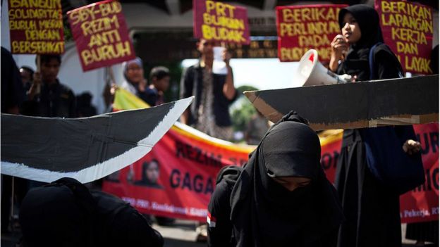 Protesta en la que se ve a dos mujeres vestidas con una burka y sobre ellas penden dos espadas hechas de cartón.