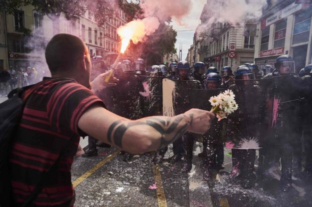 A protester faces police with a torch and a bouquet of flowers in Lyon, 26 May