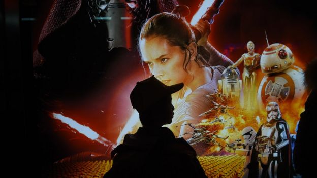 A Chinese boy waits in front of a poster for 