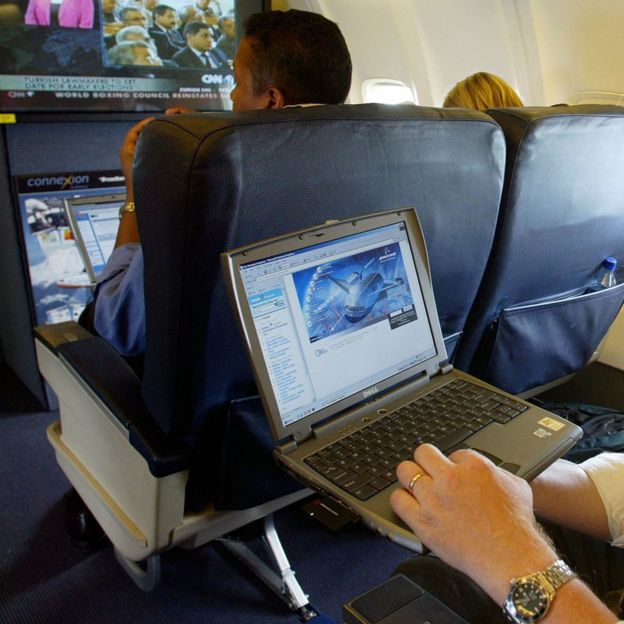 Hombre con una laptop en un avión.