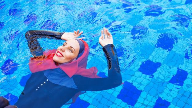 Mulher na piscina com um burkini e véu