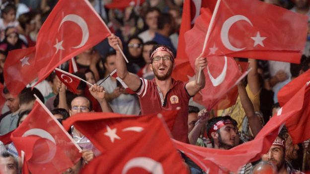 Bir gösterici ellerinde Türk bayrakları sallıyor.