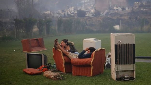 A young couple rest in a football field after a forest fire devastated Santa Olga, 26 January 2017