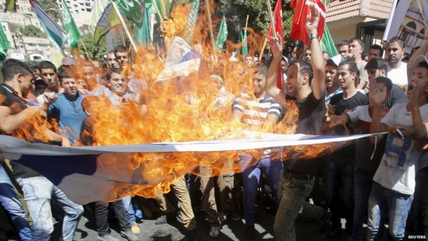 Palestinian protesters burn the Israeli flag