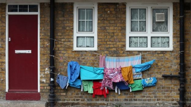 Children's clothing is hung out to dry between waste pipes in London