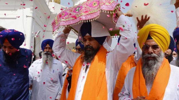 Indian Sikh priest Balwinder Singh (L) escorts the Sikh Holy Book the Guru Granth Sahib during a procession from the Gurudwara Shaheed Baba Deep Singh temple to the Gurudwara Lohgarh Sahib temple in Amritsar on June 12, 2015