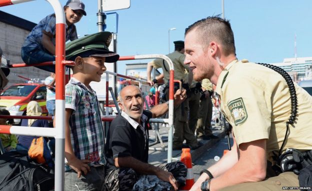 German police officer and a migrant boy joke with the officer