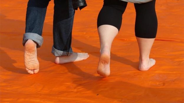 People take their shoes off to walk on the Floating Piers installation by artist Christo 18/06/2016