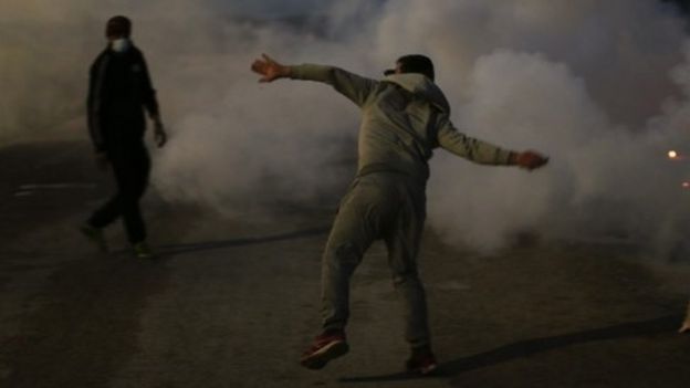 A demonstrator throws stones toward French riot police officers near the Jungle camp (22 October 2016)