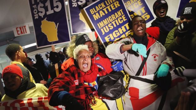 Demonstrators protesting for an increase in the minimum wage enter the media file center at the PBS NewsHour Democratic presidential candidate debate