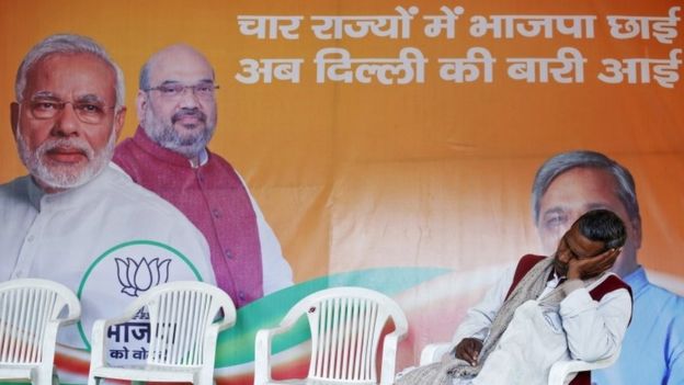 A worker of Bharatiya Janata Party (BJP) takes a nap in front of the party