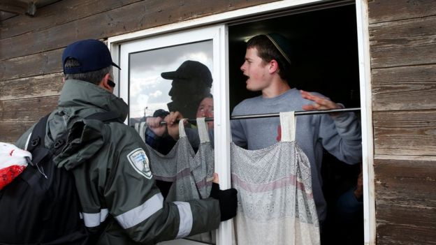 Settlers hold up a curtain role during an operation to evacuate the unauthorised settlement outpost of Amona in the occupied West Bank (1 February 2017)
