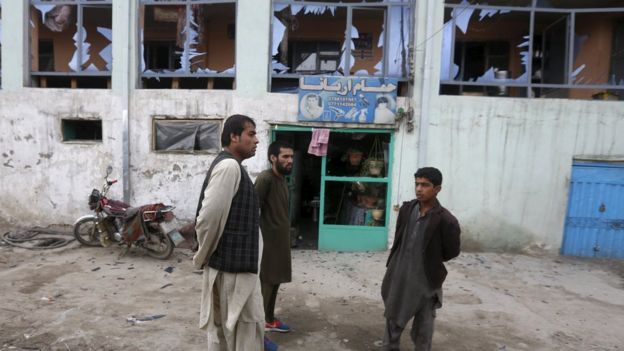 Shopkeepers inspect broken windows after a suicide attack in the Afghan capital Kabul
