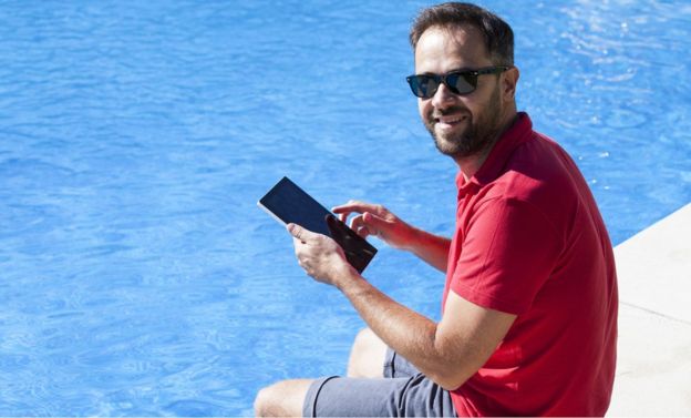 Man next to pool checking his tablet