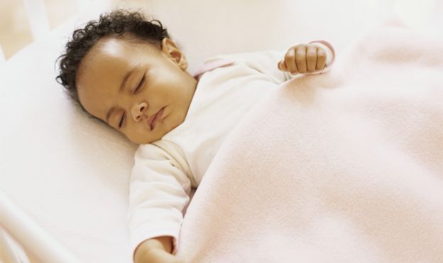 Un bebé duerme en una cuna.