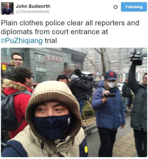 Plainclothes security official wearing a mask and a yellow smiley face sticker