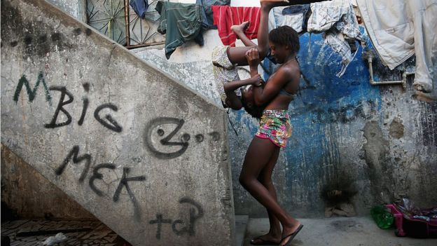 Mulher brinca com criança na Maré